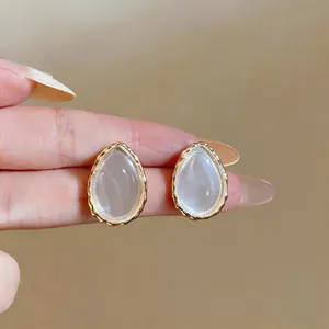 Close-up detail of teardrop-shaped resin earrings with golden frame