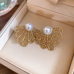 Close-up of vintage gold hollowed-out leaf earrings with elegant pearl detail