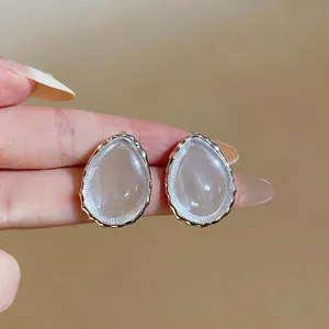 Macro detail of minimalist water drop resin stud earrings with textured silver frame