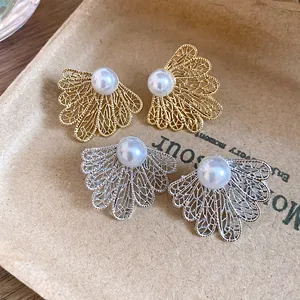 Detailed macro shot of vintage hollow leaf earrings with elegant central pearls.
