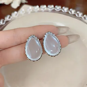 Close-up of teardrop resin stud earrings with a silver textured metal frame.