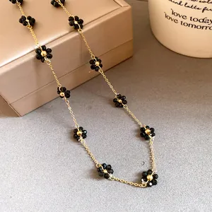 Vista dettagliata di una collana a catena dorata con fiori di perline di cristallo nero