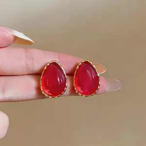 Detailed macro shot showing the vibrant red resin and gold edges of these teardrop earrings