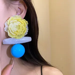 Macro shot of model wearing vintage yellow resin flower and blue bead drop earrings