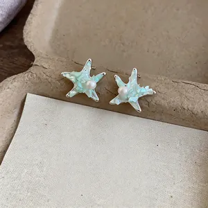Detailed view of mint green starfish earrings with a delicate central pearl