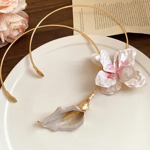 Close-up of elegant gold-tone metal choker necklaces with painted floral accents