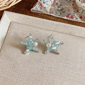 Detailed view of silver starfish stud earrings featuring blue shell inlay and center pearl