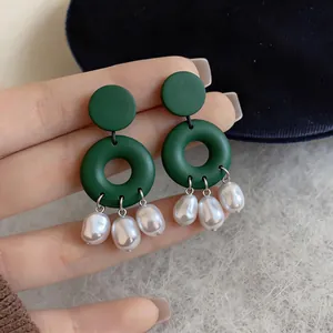 Detailed view of green geometric drop earrings with elegant dangling white pearls