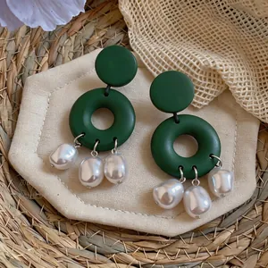 Detailed view of handmade dark green geometric earrings with white baroque pearls