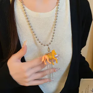 Close-up of fashionable necklace with two resin pony pendants and silver chain tassels