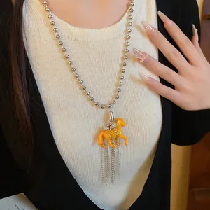 Detailed shot of yellow resin horse pendant necklace with silver ball chain tassels