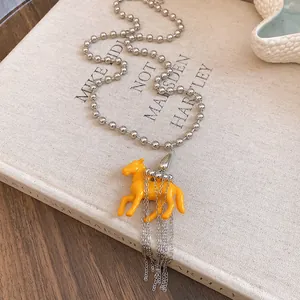 Detailed macro view of a yellow resin horse pendant on a silver ball chain necklace