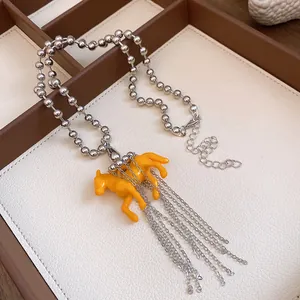 Detailed view of an orange resin horse pendant necklace with silver metal chain tassels