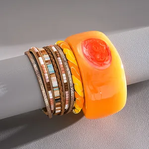 Close-up view of a bohemian leather multi-layer bracelet and orange resin bangle set