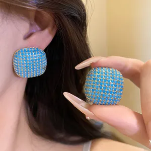 Detailed view of retro palace style square stud earrings with turquoise-blue stones.