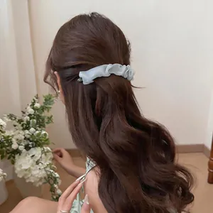 Light green pleated mesh hair clip for high ponytail styling on brunette wavy hair