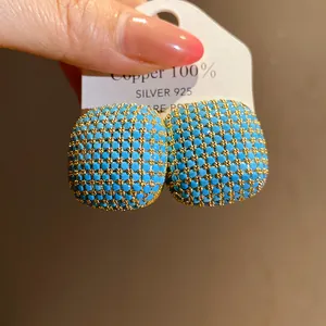 Detailed close-up of square turquoise beaded earrings with gold-tone accents
