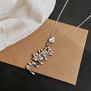 Close-up of exquisite silver tassel necklace with water drop and heart pendants on brown card.