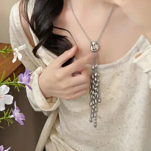 Detail view of an elegant silver teardrop tassel necklace worn by a female model.