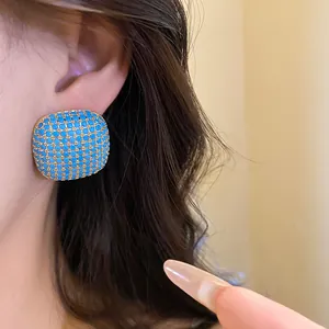 Detailed macro view of vintage square stud earring featuring turquoise stones on a model's ear