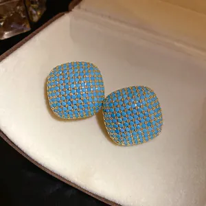 Detailed macro shot of vintage palace style square stud earrings with blue stone inlay design