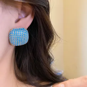 Close-up of vintage blue square stud earrings featuring a textured gold-tone base.