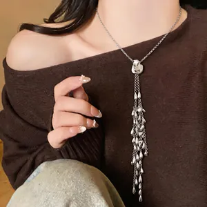 Close-up of a silver tassel necklace with heart and water-drop pendants on a model