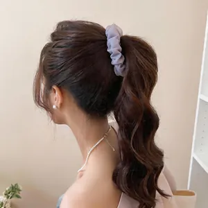 Close-up detail of a lavender mesh pleated hair clip securing a wavy high ponytail.