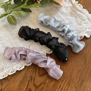 Detail view of mesh pleated twist banana hair clips in grey, black, and purple colors