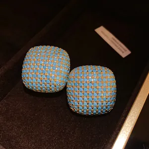 Macro detail of vintage court style square stud earrings with light blue beads in gold grid