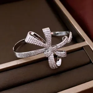 Silver bow-shaped open bangle plated in 18K gold and inlaid with cubic zirconia