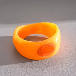 Detail view of a bold chunky orange resin bangle with textured marbled oval inlay