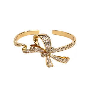 Elegant 18K gold plated open bangle featuring a sparkling zircon encrusted twisted bow design.