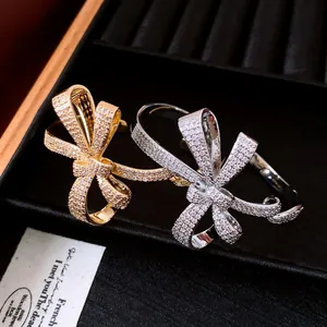 Detail view of two elegant 18K gold plated bow bangles encrusted with sparkling zircon.