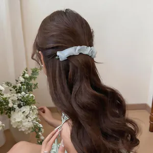 Elegant light blue pleated mesh hair clip shown in a stylish half-up hairstyle