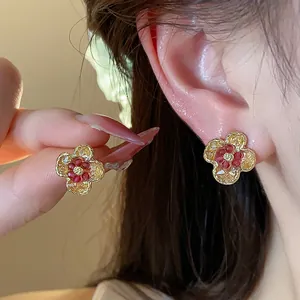 Primo piano di delicati orecchini a forma di fiore con cristalli rossi e gialli.