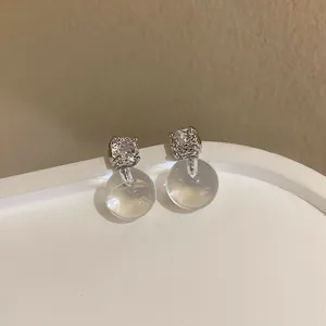 Vista dettagliata di orecchini minimalisti in argento con zircone e sfera di vetro trasparente