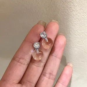 Primo piano di orecchini a perno in zircone con perle di vetro ambrate