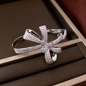 Detailed view of silver-tone bow bangle paved with sparkling cubic zirconia