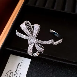 Macro view of a luxury 18K gold plated zircon encrusted bow open bangle in a black box
