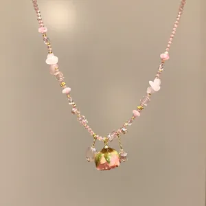 Dettaglio di una collana artigianale di cristallo rosa con ciondolo a forma di rosa stabilizzata.