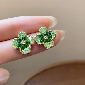 Dettaglio di orecchini a lobo a forma di fiore in vetro sfumato verde con cornice dorata.