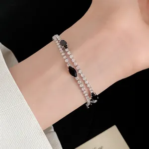 Primo piano di un bracciale in zircone a doppio strato con pietre nere sul polso.