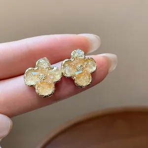 Dettaglio macro di eleganti orecchini a lobo a forma di fiore in vetro dorato sfumato