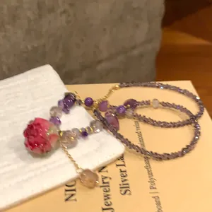Dettaglio di una collana di perle di cristallo con un ciondolo a forma di rosa rosa eterna.