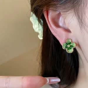Primo piano dettagliato di un elegante orecchino a fiore in vetro verde sull'orecchio