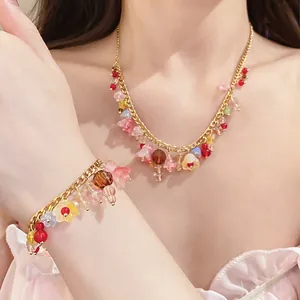 Detailopname van kleurrijke harsbloemkwastjes op een gouden ketting- en armbandset