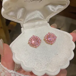 Dettaglio di orecchini a perno con zirconi rosa in un portagioie a forma di conchiglia