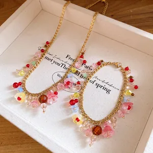 Detail van een gouden roestvrijstalen ketting met kleurrijke bloemen van hars en kralen