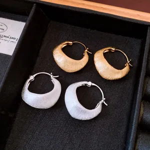 Detail view of 18K gold plated brushed texture hoop earrings in gold and silver.